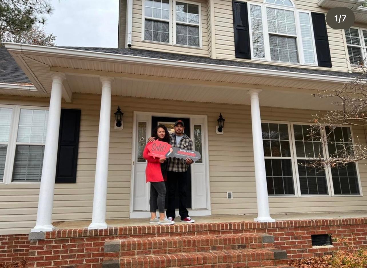 Couple in front of their new home with sold sign